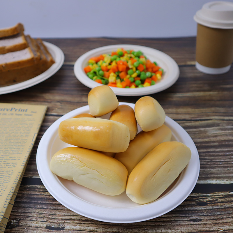 White plates with bread and vegetables beside a lidded paper cup